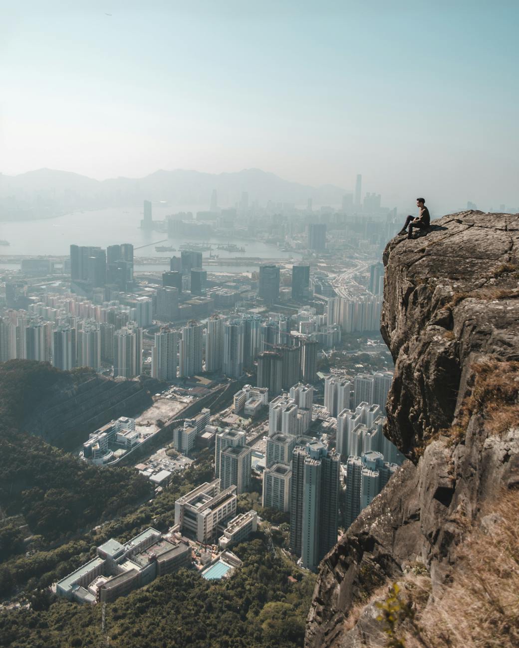 man sitting on mountain overviewing metropolitan building