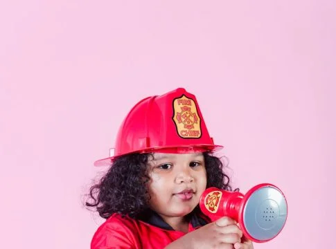 little ethnic girl in fireman costume using loudspeaker