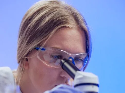 close up view of a woman examining a microscope slide